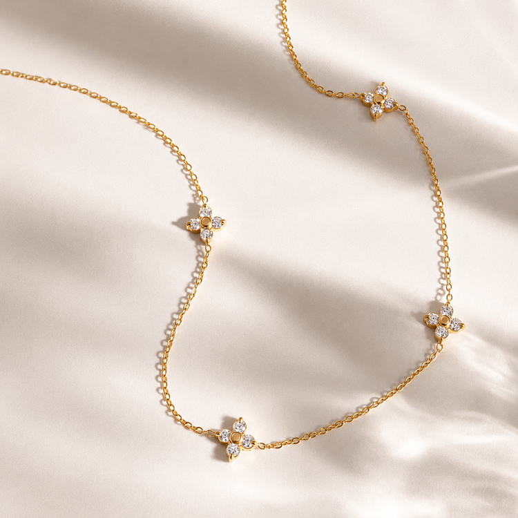 Flat lay of the Ari Floral Necklace with sparkling flower stations on a delicate gold chain