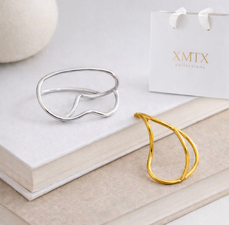 Billy Geometric Double Ring in gold and silver displayed on neutral books with XMTX Collections packaging