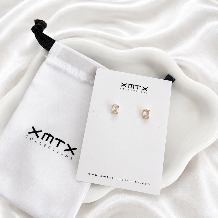 Brenda clear stud earrings displayed on an XMTX Collections jewelry card with branded pouch