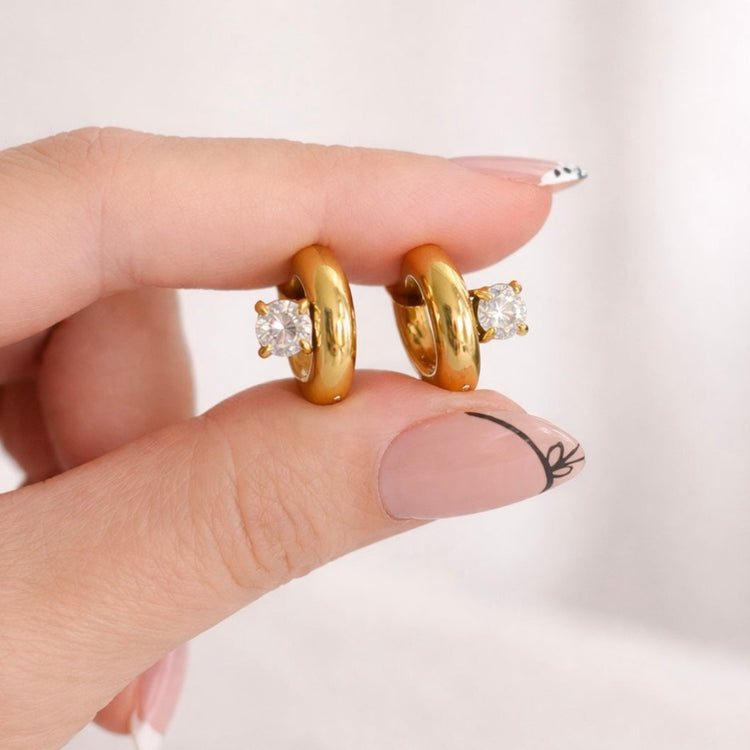 Elle Huggies gold round stone huggie earrings held in hand close-up