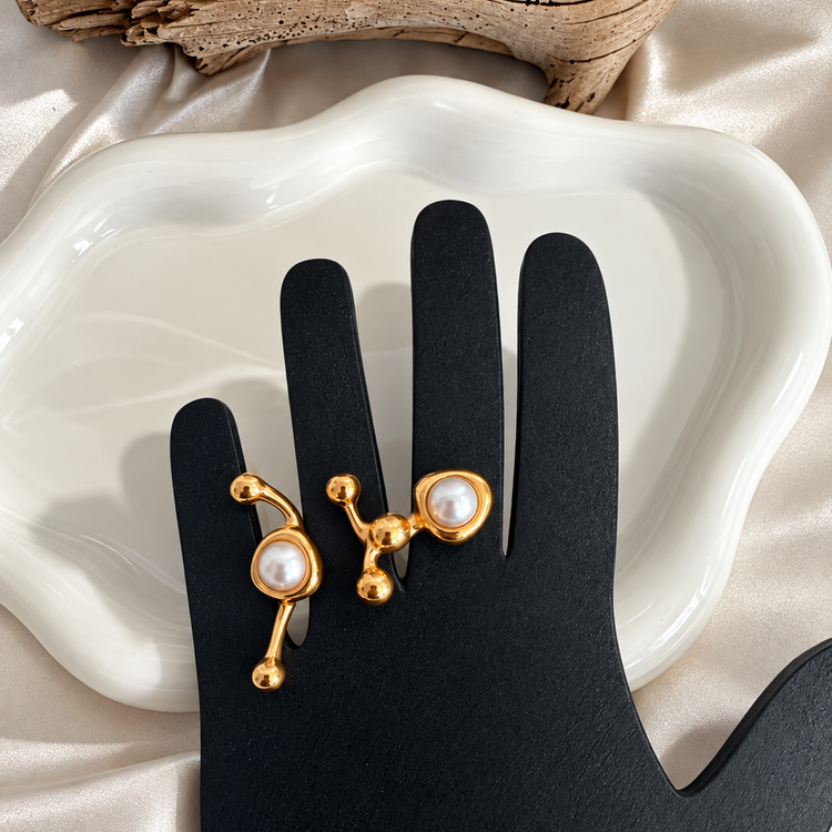 Ellen Modern Ring displayed on a black hand-shaped jewelry stand, highlighting its sculptural gold design and faux pearls