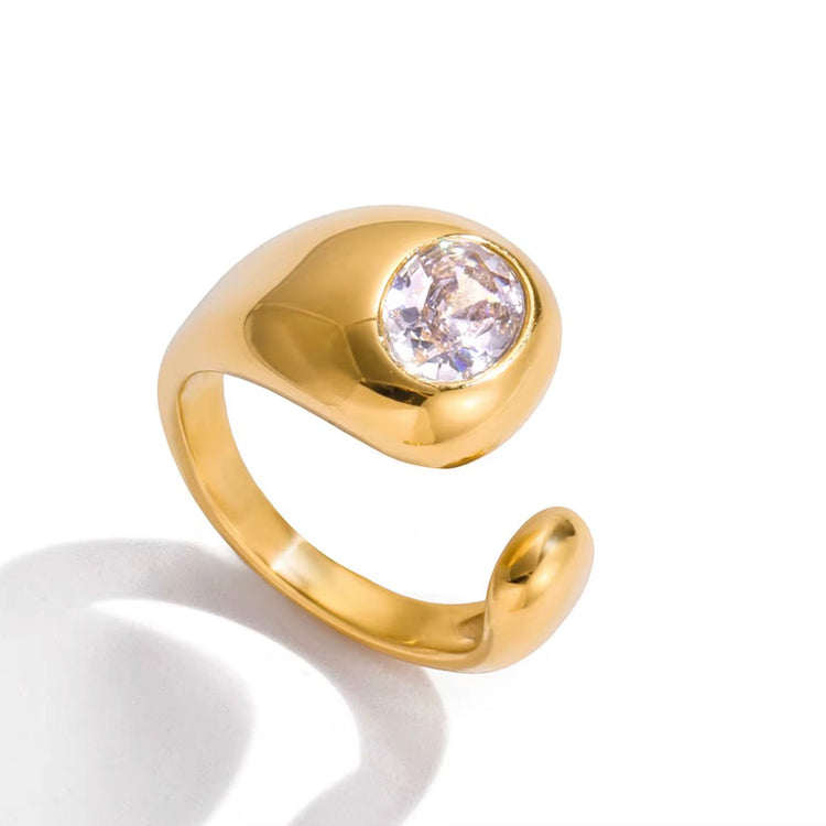 Gold Jennie Ring with polished sculptural band and round crystal stone on white background.