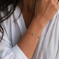 Woman wearing 14K gold plated sterling silver blue opal evil eye bracelet