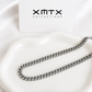 8mm silver Cuban chain necklace displayed on a white ceramic dish
