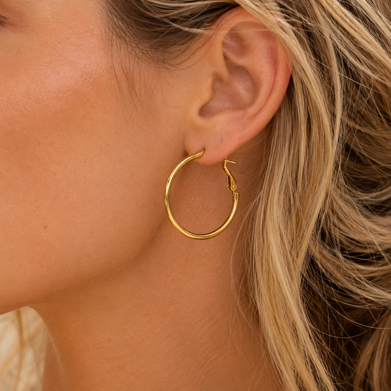 Model wearing Dulcie medium gold hoop earrings, lightweight waterproof and hypoallergenic hoops designed for everyday wear.