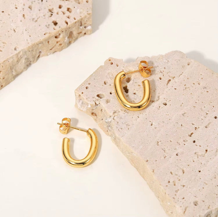 Alicia gold hoop earrings displayed on textured stone surface