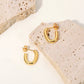 Alicia gold hoop earrings displayed on textured stone surface