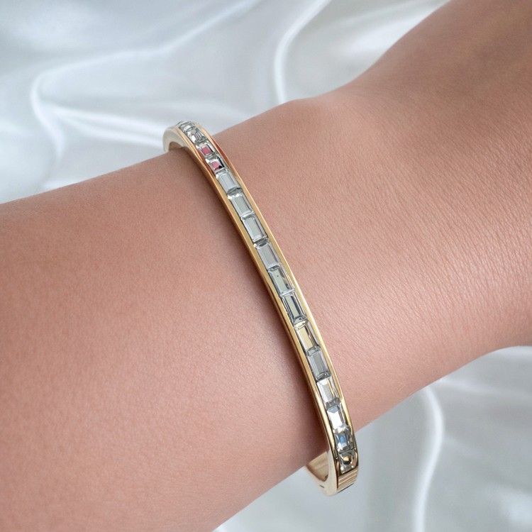 Woman wearing the gold Ally bangle bracelet with baguette-cut stones