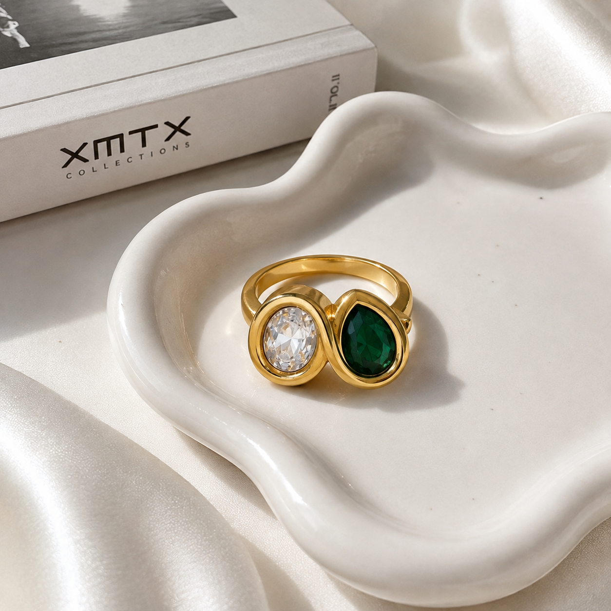 Aster waterproof gold double stone ring displayed on a white ceramic jewelry dish with XMTX Collections packaging