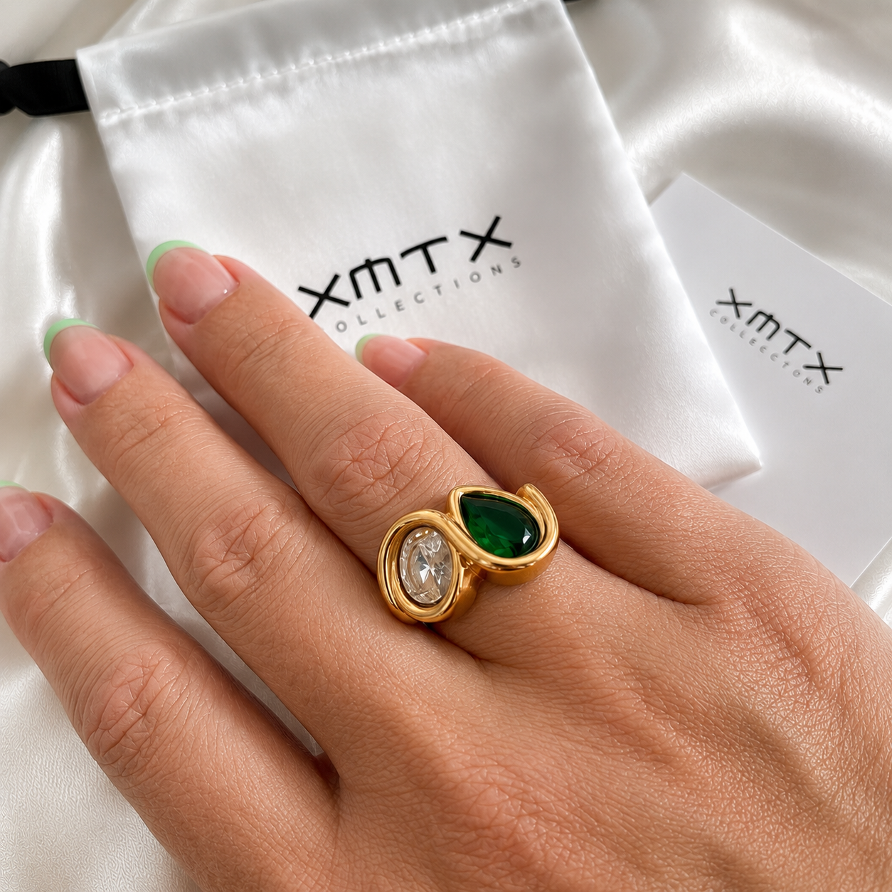 Model wearing the Aster waterproof gold double stone statement ring with emerald green and clear stones.