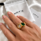 Model wearing the Aster waterproof gold double stone statement ring with emerald green and clear stones.