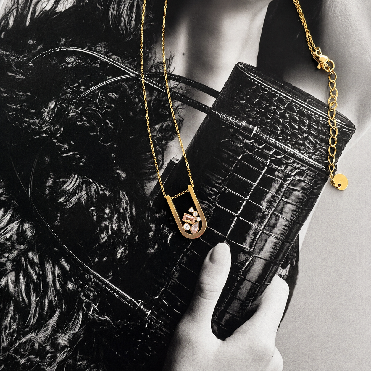 Modern gold Bianka necklace with sparkling multi-cut cubic zirconia pendant styled on a fashion editorial background.