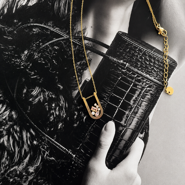Modern gold Bianka necklace with sparkling multi-cut cubic zirconia pendant styled on a fashion editorial background.