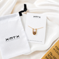aterproof gold Bianka pendant necklace displayed on XMTX Collections jewelry card with branded pouch.