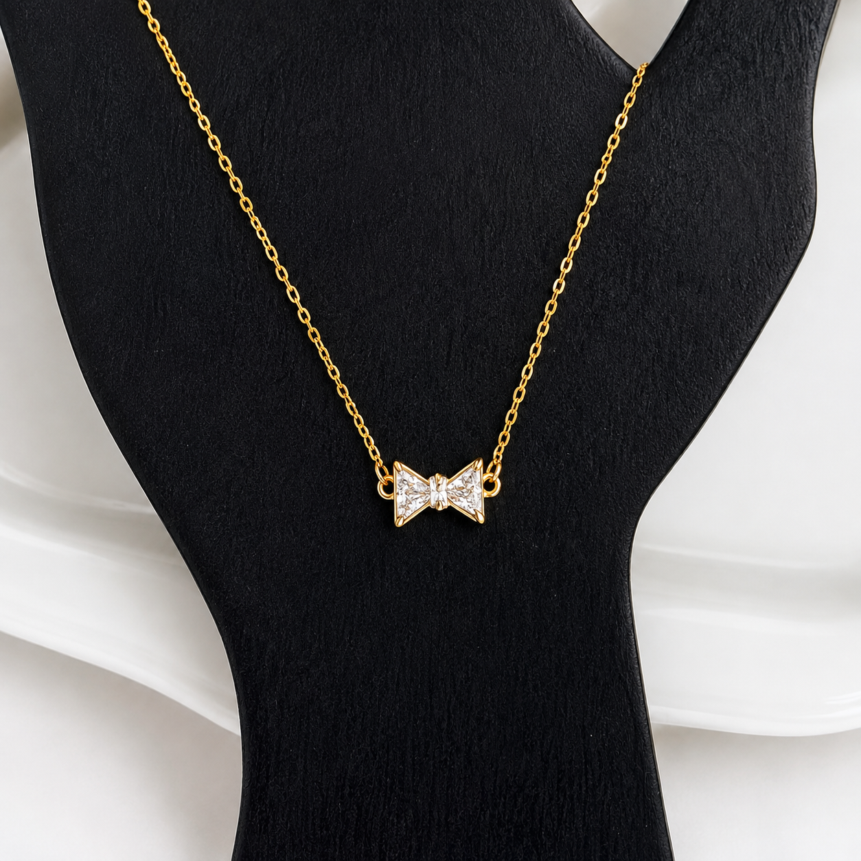 Gold Bow Rhinestone Necklace displayed on a black jewelry bust showing the rhinestone bow pendant