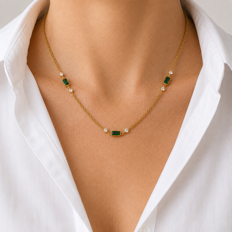 Model wearing the Brielle waterproof gold necklace with emerald-green baguette stones and cubic zirconia accents