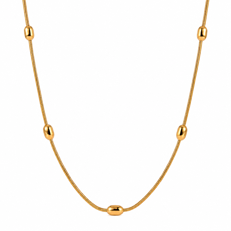 Gold snake chain necklace with oval bead accents on a white background