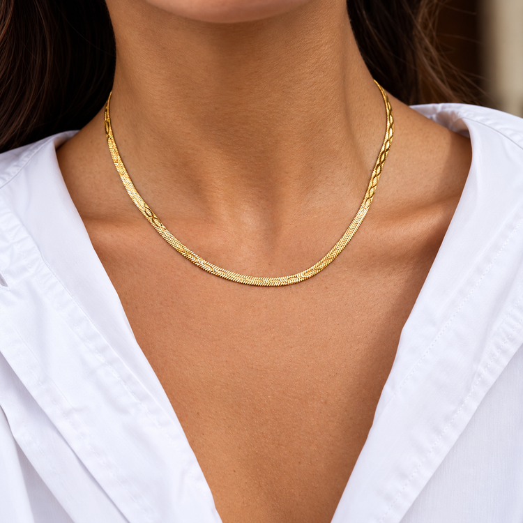 Embossed gold herringbone necklace worn on model, featuring a sleek textured chain design