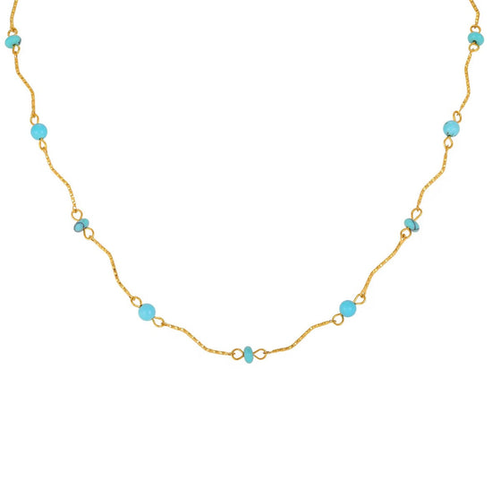 A delicate gold chain necklace featuring small, evenly spaced light blue beads on a plain white background.
