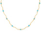 A delicate gold chain necklace featuring small, evenly spaced light blue beads on a plain white background.