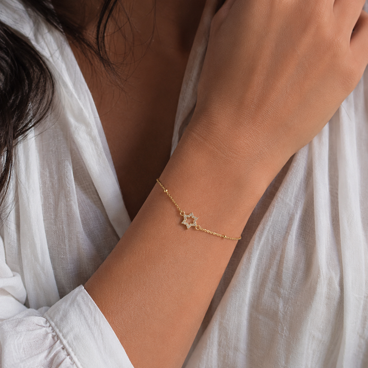 Woman wearing gold pavé Star of David bracelet in natural lighting
