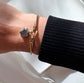 Gold bracelet with heart charm on a wrist against a white background