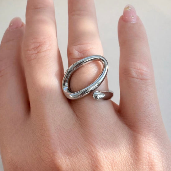 Silver open-end statement ring with oval loop design worn on hand, made of polished stainless steel, non-tarnish and waterproof by XMTX Collections
