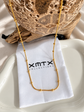 Lyssa Bead Chain Necklace styled on an XMTX Collections jewelry pouch, featuring a delicate gold bead chain