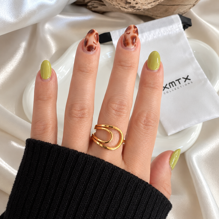 Close-up of the Nico Sculptural Ring highlighting its smooth gold finish and curved bands