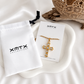 Gold cross necklace displayed with XMTX Collections jewelry packaging