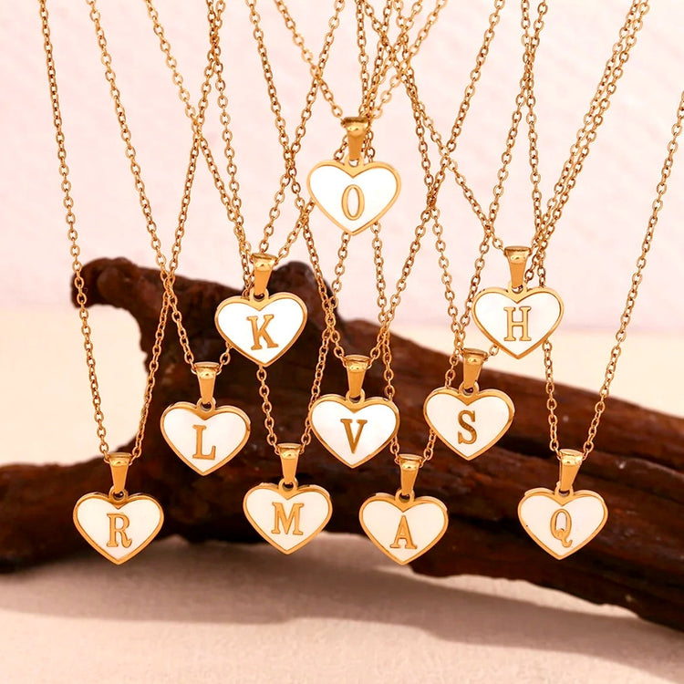 Display of personalized Mother of Pearl heart initial necklaces with gold chains. Waterproof, hypoallergenic, non-tarnish jewelry by XMTX Collections