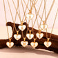 Display of personalized Mother of Pearl heart initial necklaces with gold chains. Waterproof, hypoallergenic, non-tarnish jewelry by XMTX Collections