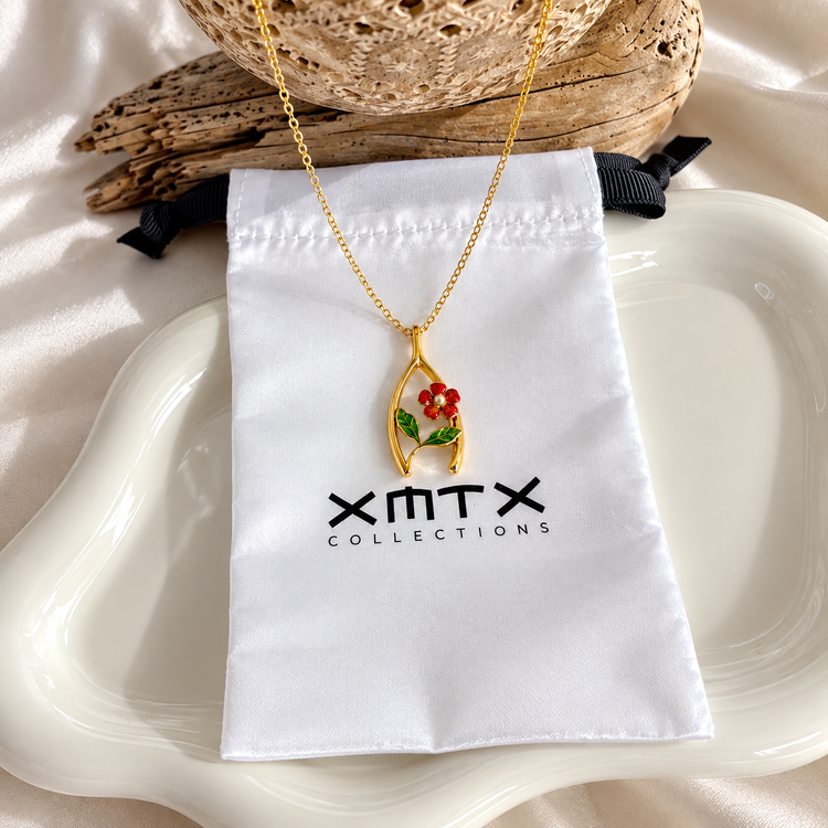 Poppy Wishbone Necklace styled on XMTX Collections jewelry pouch, featuring a floral gold pendant