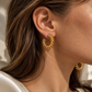 Raya Coil Hoops gold statement earrings worn on model, featuring a textured coil design