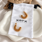 Raya Coil Hoops gold waterproof earrings shown with XMTX Collections jewelry pouch