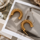 Raya Coil Hoops sculptural gold hoop earrings styled in a modern jewelry flatlay