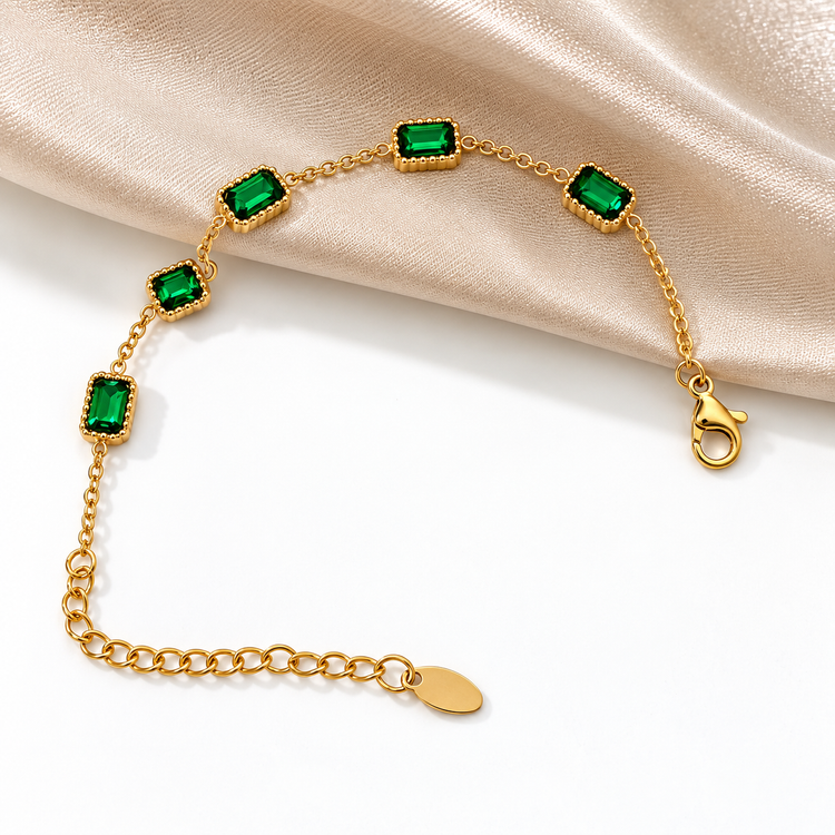 Reese Bracelet with emerald green stones displayed on satin