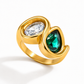 Waterproof gold statement ring featuring a clear oval cubic zirconia and emerald green pear-cut stone.