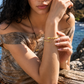 Model wearing a gold waterproof snake bangle bracelet by XMTX Collections at the beach