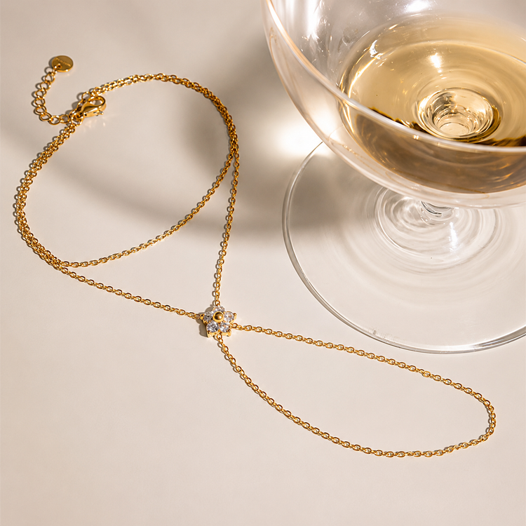 Single Flower Hand Chain with a cubic zirconia flower centerpiece styled in a luxury flat lay, showcasing waterproof, non-tarnish gold jewelry