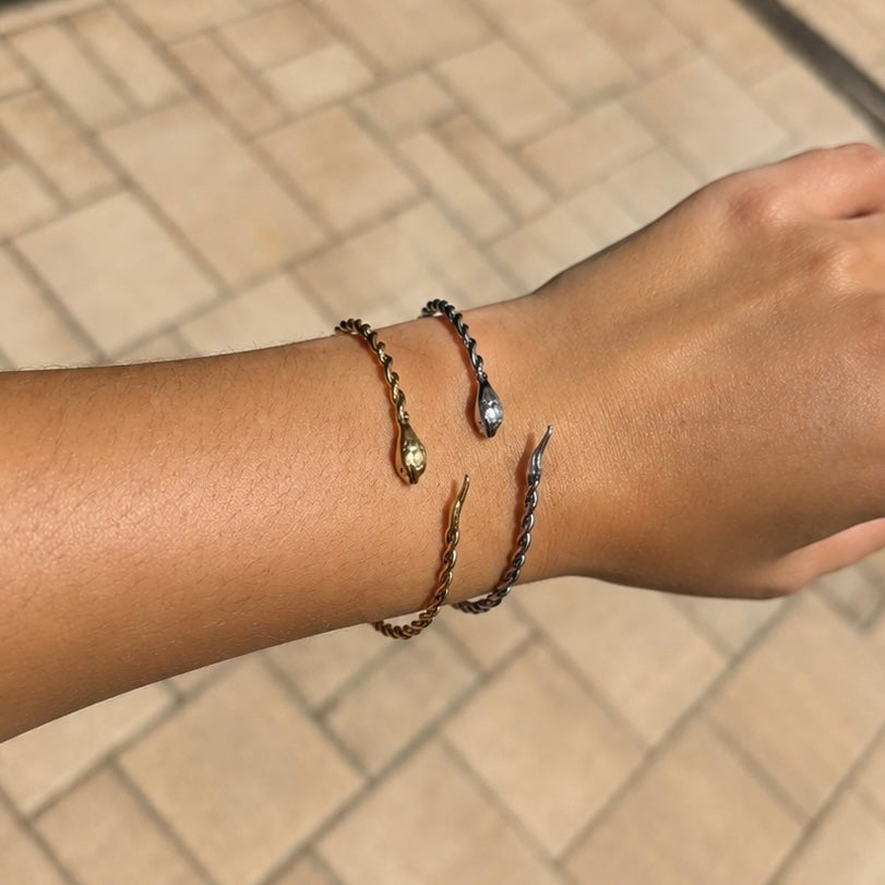 Gold and silver snake bangle bracelets worn together on the wrist, featuring waterproof non tarnish stainless steel 