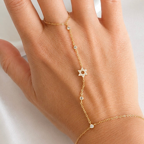 Sterling silver Star of David hand chain with clear cubic zirconia accents shown worn on the hand in a gold finish.