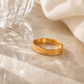 Sun Ring engraved gold band displayed in a luxury editorial flat lay with natural light