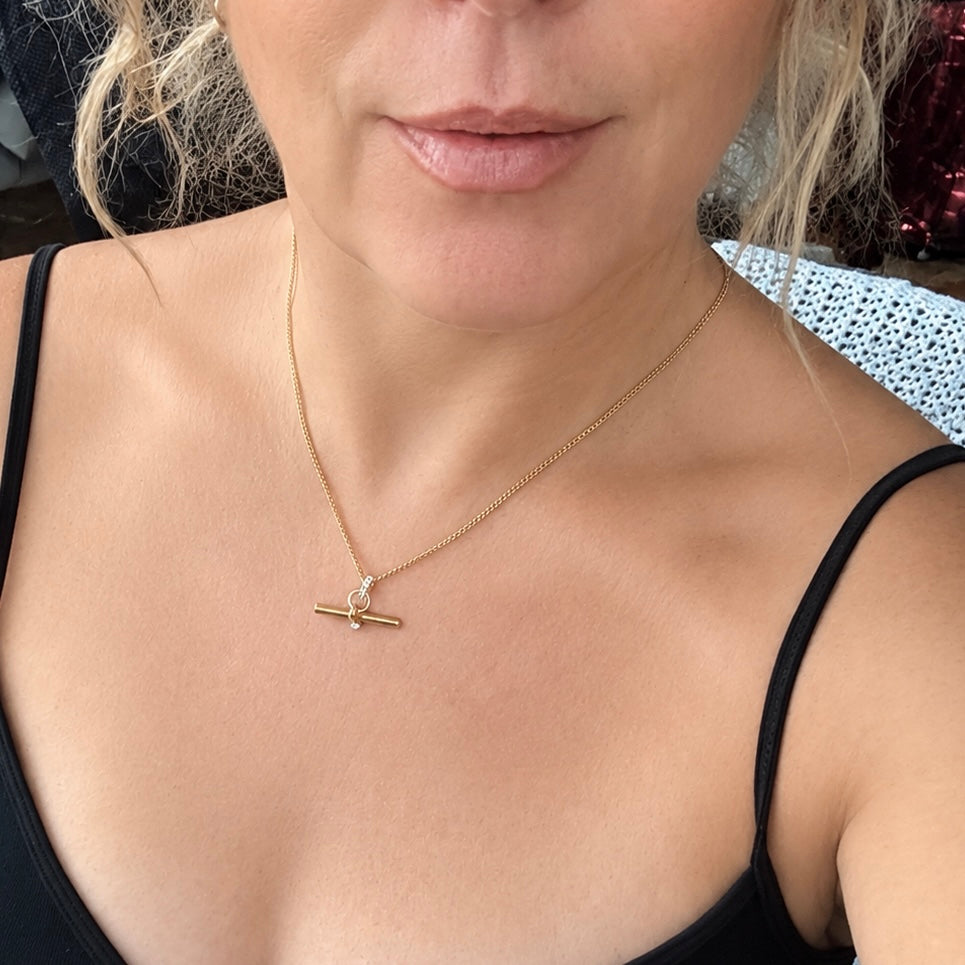 Woman wearing a waterproof non-tarnish gold T Bar necklace with crystal accent. Minimalist everyday jewelry styled for a modern look