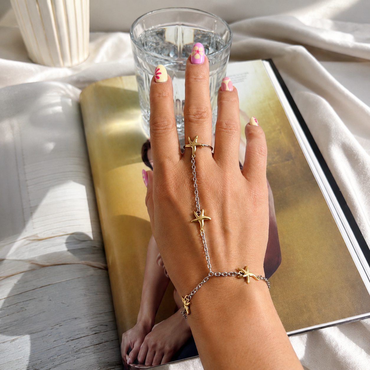 Woman wearing the Two Tone Starfish Ring Hand Chain with an adjustable ring and waterproof mixed-metal starfish design