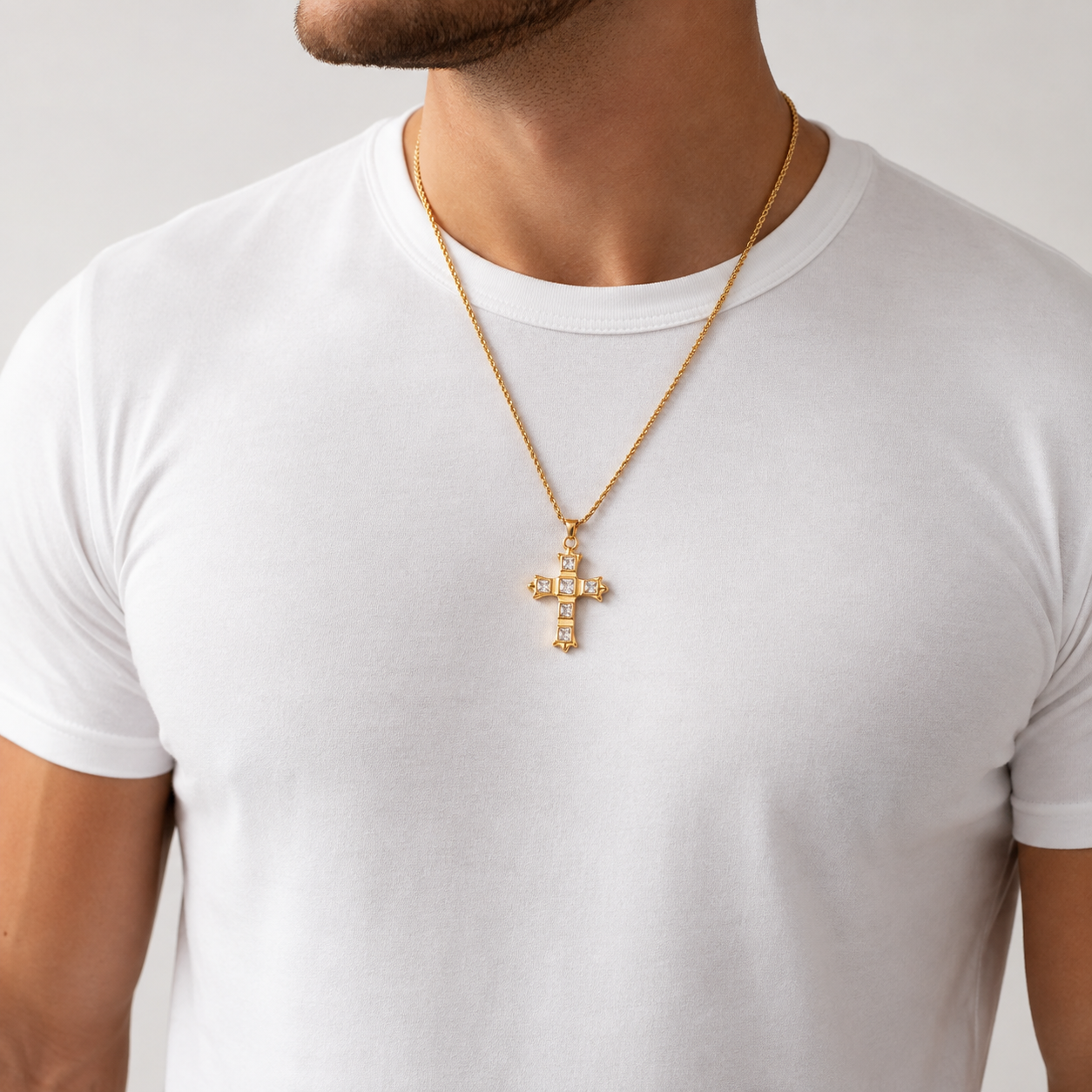 Unisex gold cross necklace with clear stone accents worn on a man