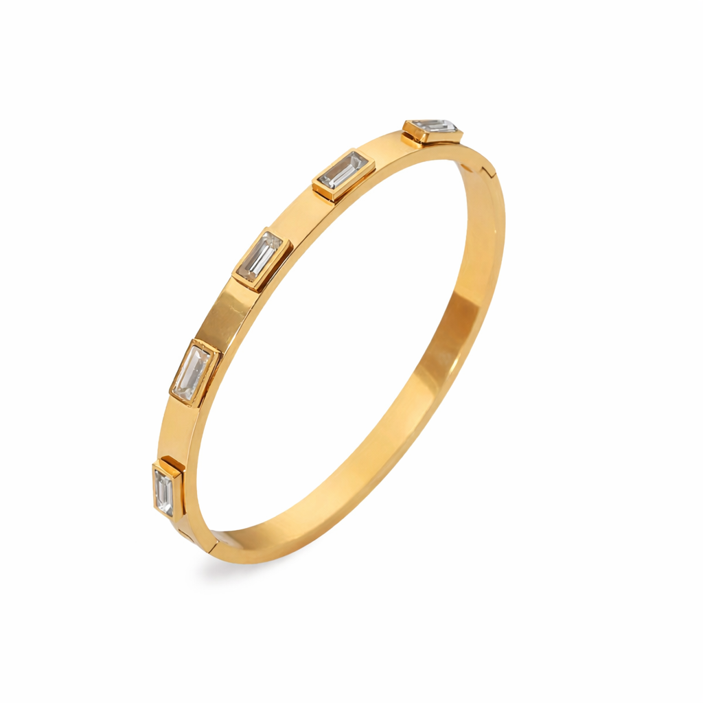 Gold Abby bangle bracelet with five clear baguette stones on a white background