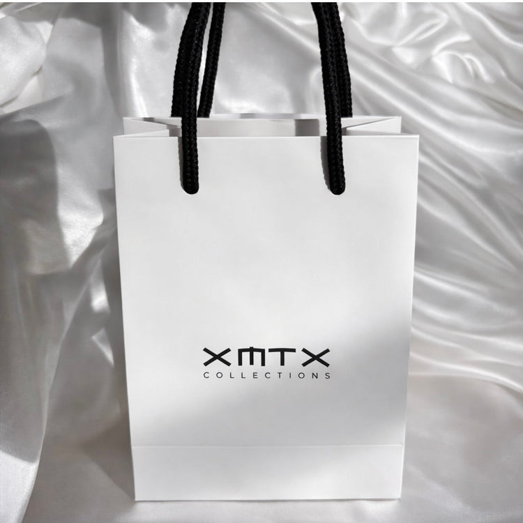 Back view of XMTX Collections white gift bag with black rope handles, minimalist luxury jewelry packaging