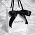 XMTX Collections signature white gift bag with black rope handles and logo, luxury jewelry packaging front view