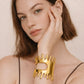 Woman wearing gold statement cuff bracelet with drip design, luxury bold jewelry styling
